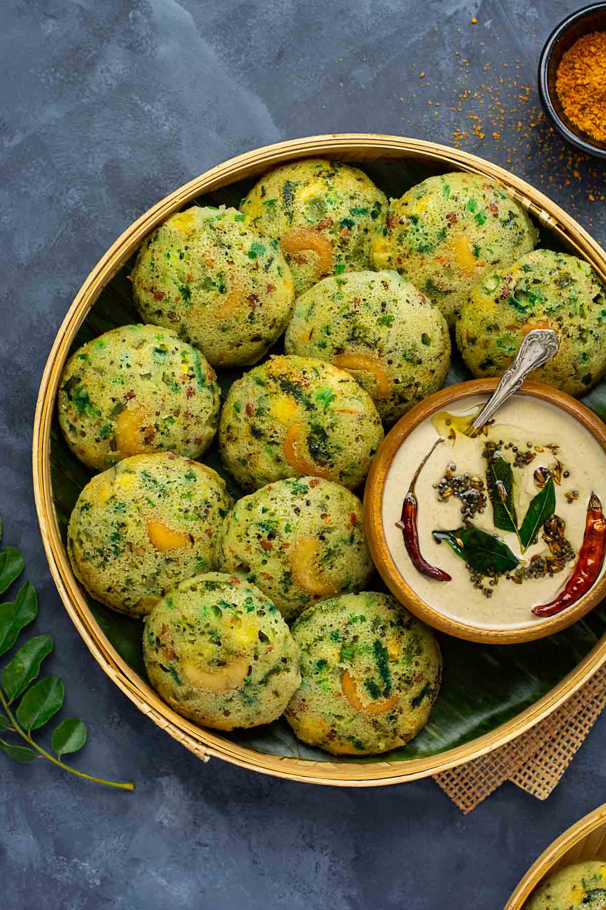 Rava idlis a bowl of peanut chutney placed on a bamboo plate lined with banana leaf